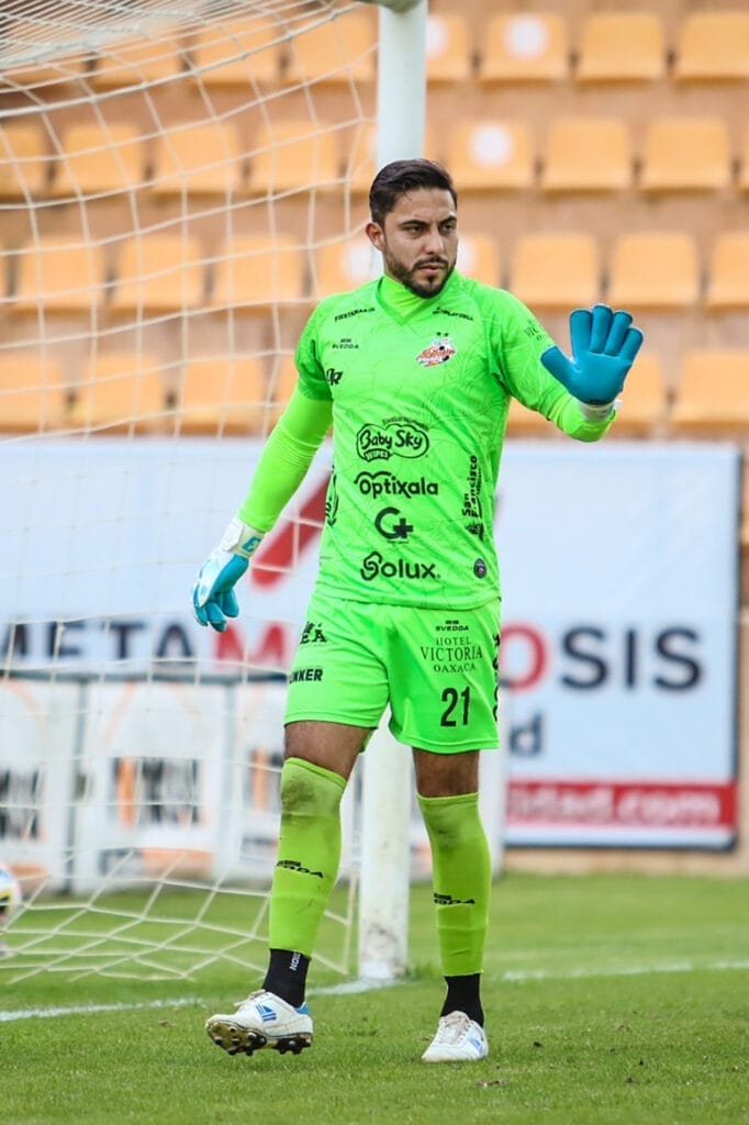 Eduardo Fernández, Alebrijes goalkeeper from Mexico wearing NYK gloves, making a save in bright green uniform during match play.