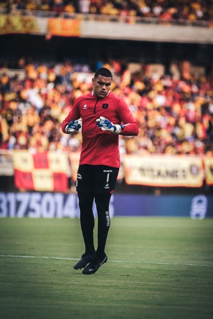 Joel Graterol wearing NYK goalkeeper gloves while warming up at América de Cali stadium, professional Colombian goalkeeper known for fast reflexes and fearless performance.